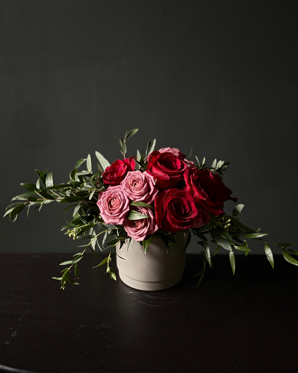 Bouquet of red and pink roses in a white box on a dark background