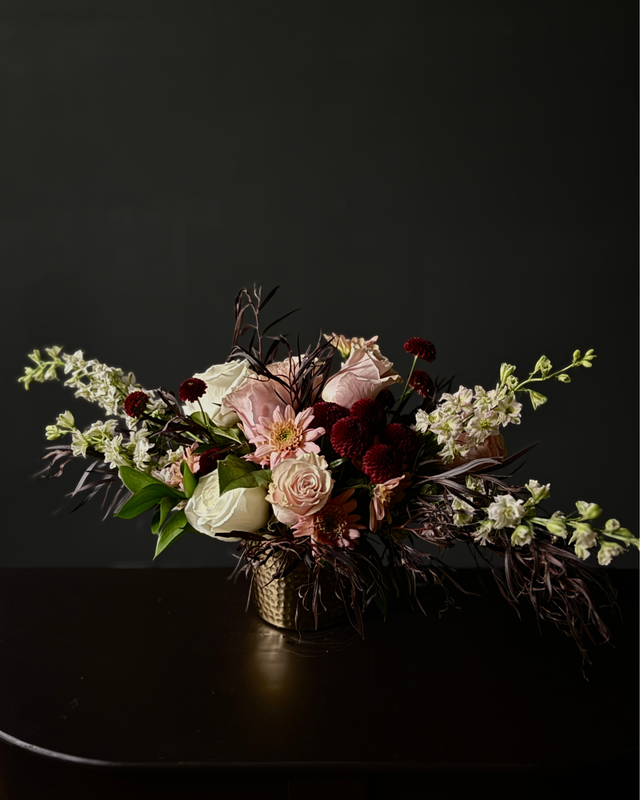 Floral arrangement in a vase on a dark surface with a black background