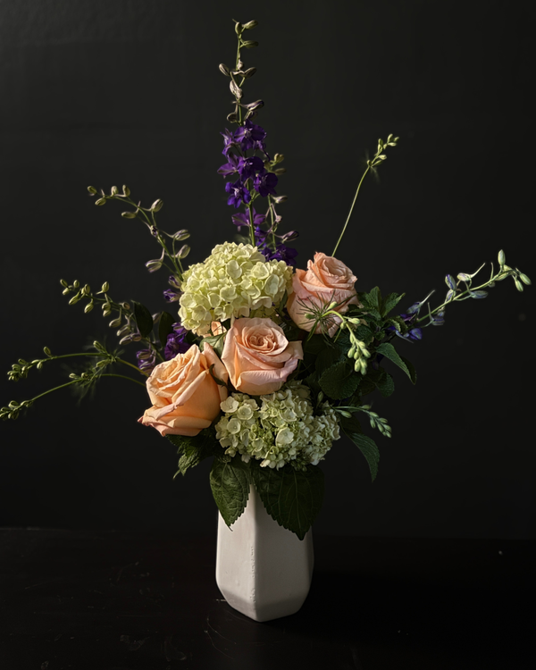 Floral arrangement in a white vase against a black background